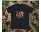 Black t-shirt with a colorful dinosaur and monster truck graphic on a wooden background with toy vehicles and plants.