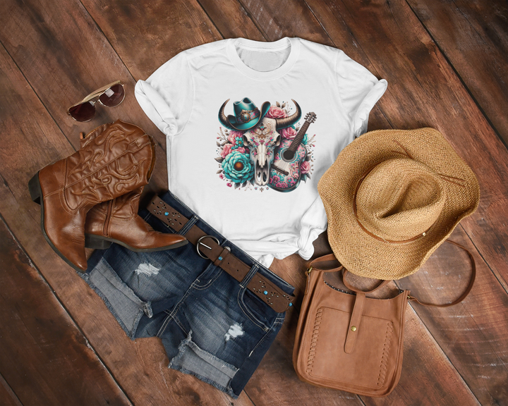 White t-shirt with skull design, cowboy boots, hat, and purse on a wooden surface