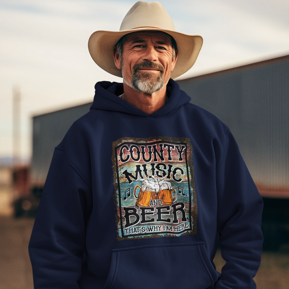 Man wearing a navy hoodie with 'County Music and Beer That's Why I'm Here' design, standing outdoors.